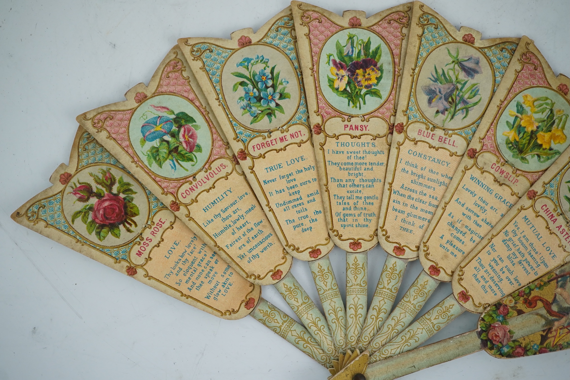 Three novelty fans with a mixed Brussels lace fan and black lace fan, a small language of love in flowers fan, a paper windmill advertising French Café fan, a carved cream Bakelite fan, a black and gilt, lace and sequin